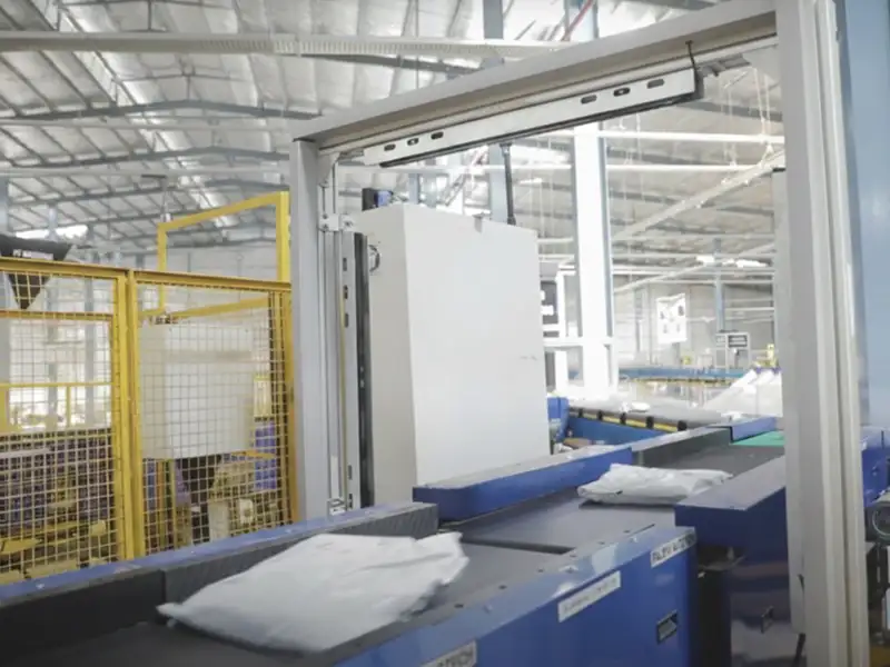 Packages on an Amazon conveyor belt with black UHMW guide rails.