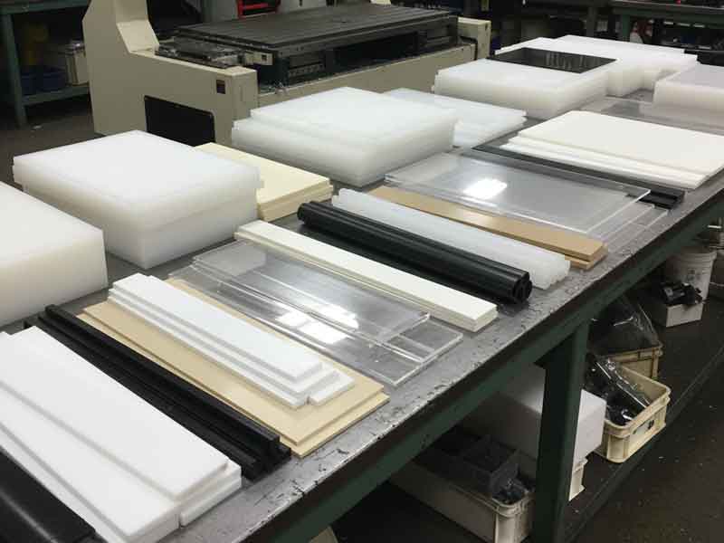 A table with white, black, and clear plastic sheets and rods.